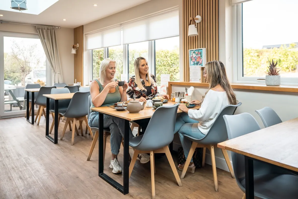 Three women sat at a table with coffee